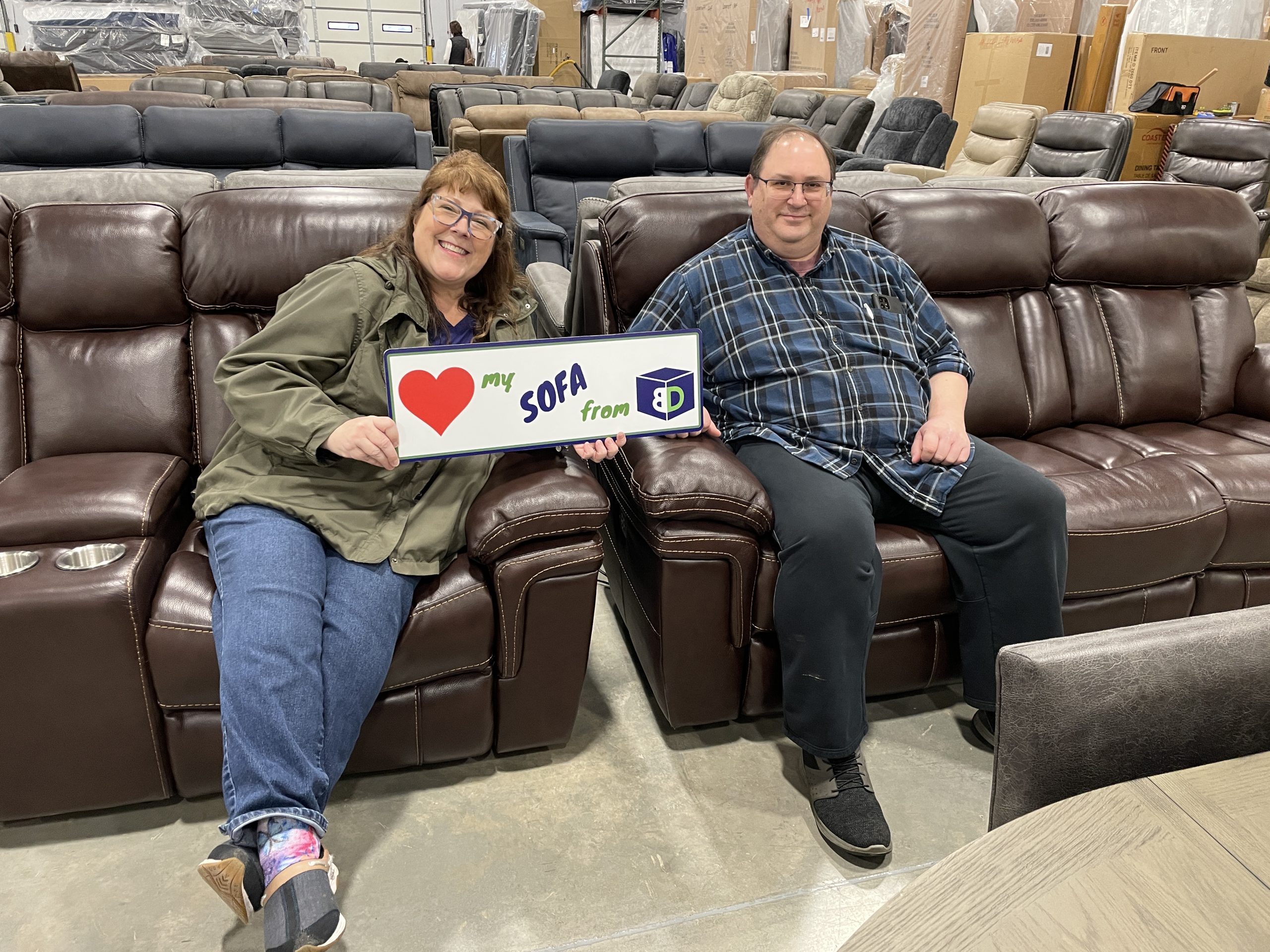 BoxDrop North Idaho customers Greg and Gia with their new burgundy leather sofa and loveseat